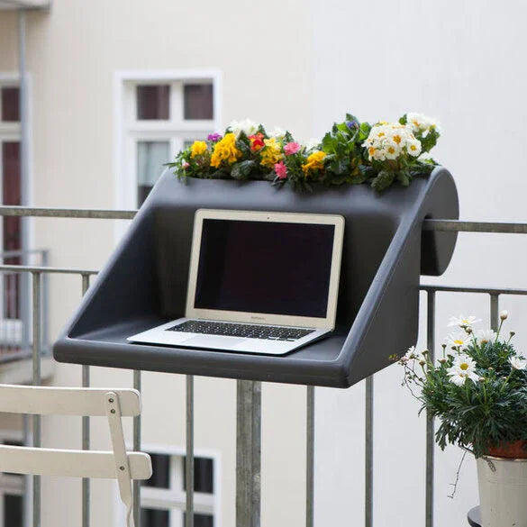 Ein Balkonarbeitsplatz mit einem Laptop auf einem stilvollen schwarzen Regal, geschmückt mit bunten Blumen, was die Ästhetik des Arbeitsplatzes im Freien unterstreicht.