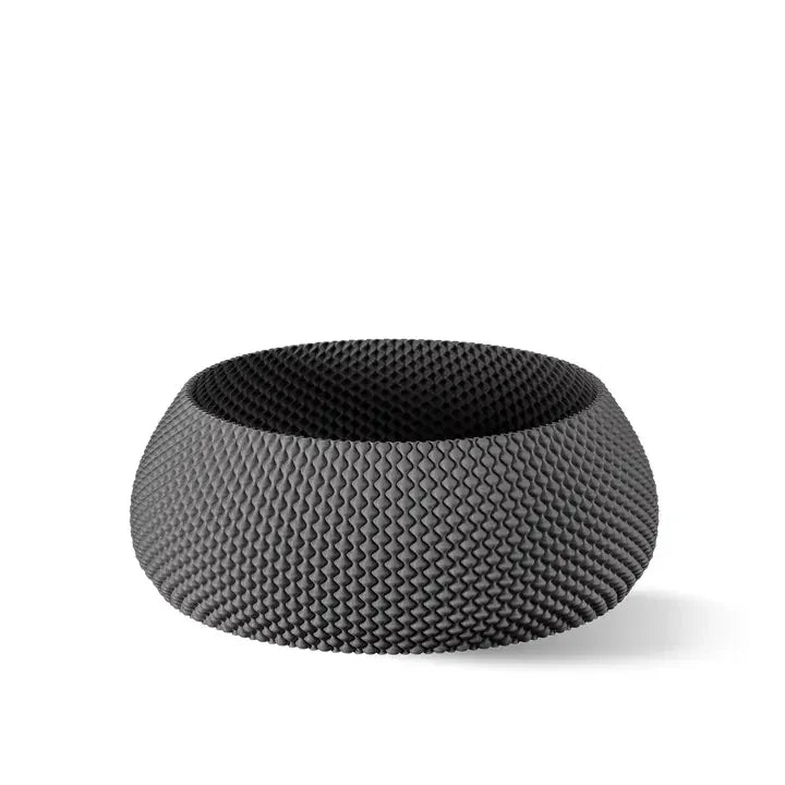 Eine stilvolle, runde schwarze Schüssel mit strukturiertem Zickzackmuster vor einem schlichten weißen Hintergrund.