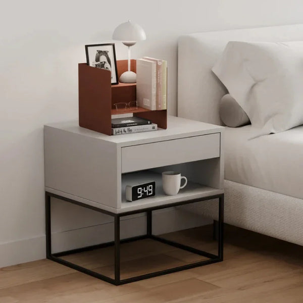 Moderner Beistelltisch mit Buchablage, Lampe, Uhr und Tasse neben einem Bett