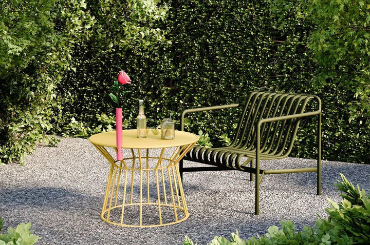 Moderner Gartenstuhl aus Metall und gelber Beistelltisch mit Blume und Getränken auf Kies