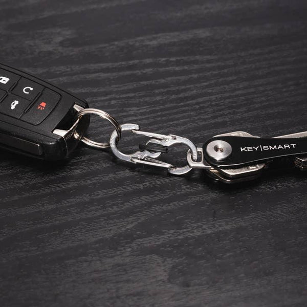 Autoschlüssel mit KeySmart Schlüsselorganizer und Metall-Karabiner auf schwarzem Holztisch