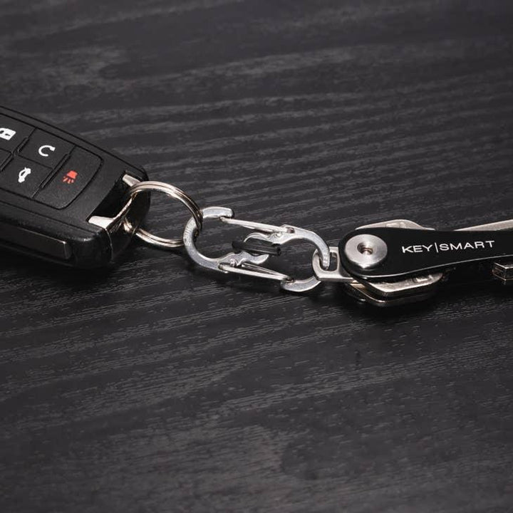 Autoschlüssel mit KeySmart Schlüsselorganizer und Metall-Karabiner auf schwarzem Holztisch