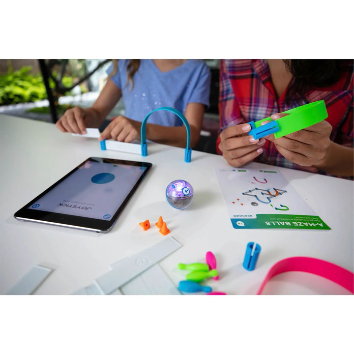 Kinder spielen mit Sphero Roboter, Tablet und buntem Lernspielzeug auf weißem Tisch