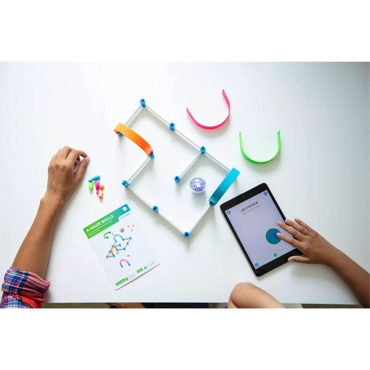 Kinder bauen Robotik-Kugelbahn mit Tablet-Steuerung und Bauanleitung auf weißem Tisch