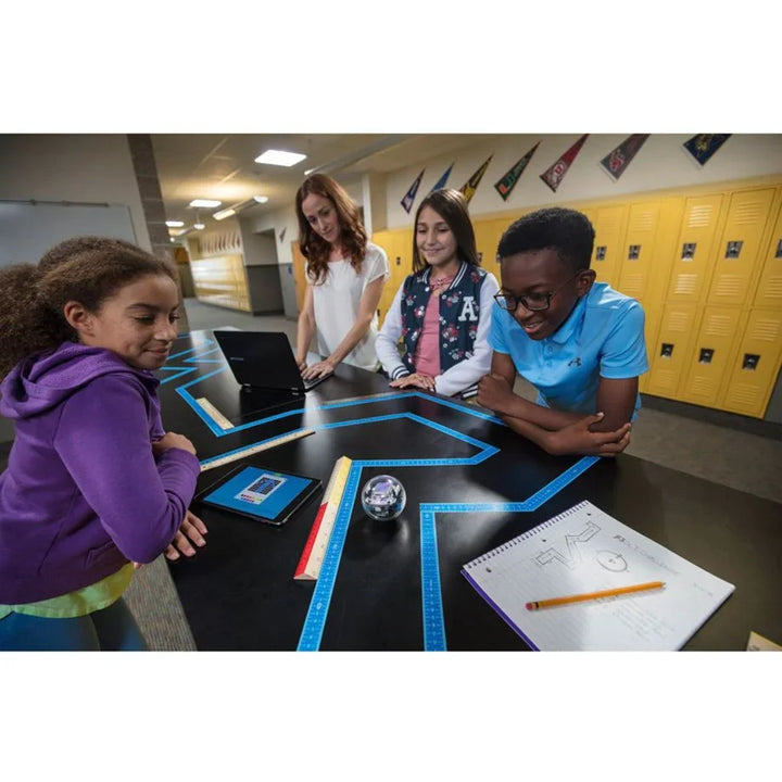 Kinder und Lehrerin programmieren Roboter im Klassenzimmer mit Linealen und Tablet