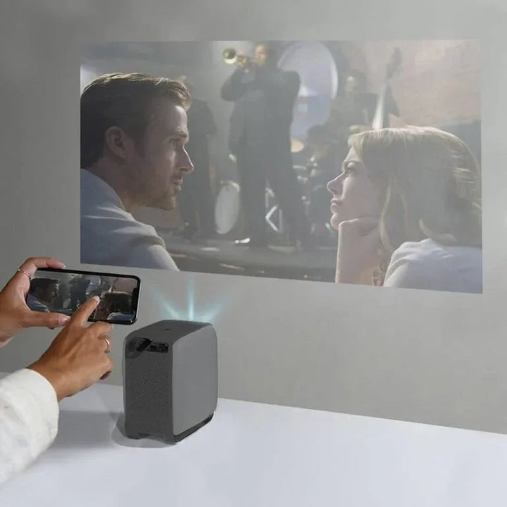 Mobiler Mini Beamer projiziert Film von Smartphone auf weiße Wand, Heimkino Atmosphäre