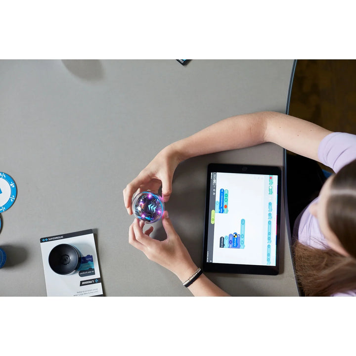 Mädchen programmiert Roboter mit Tablet, Coding-Lernspielzeug auf Tisch, Robotik für Kinder