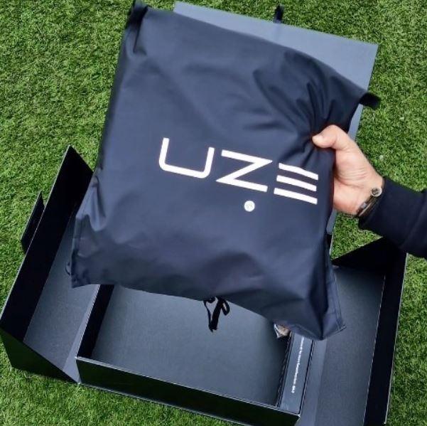 Tech-Jacke in schwarzem UZE-Beutel, Verpackung auf grünem Rasen, moderne Mode